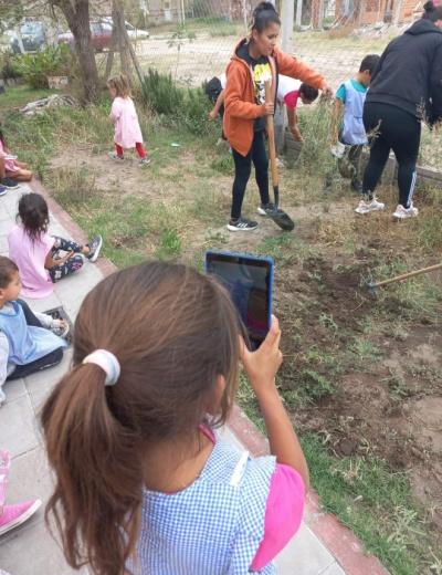 Fotografía de una nena con una tablet en un espacio verde.