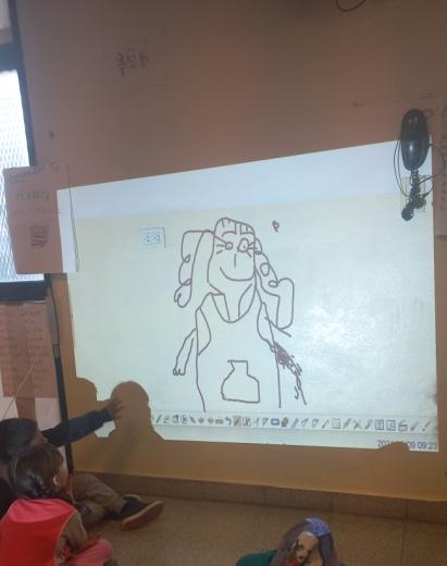 Nenes viendo sus dibujos en la pizarra que se refleja en una pared